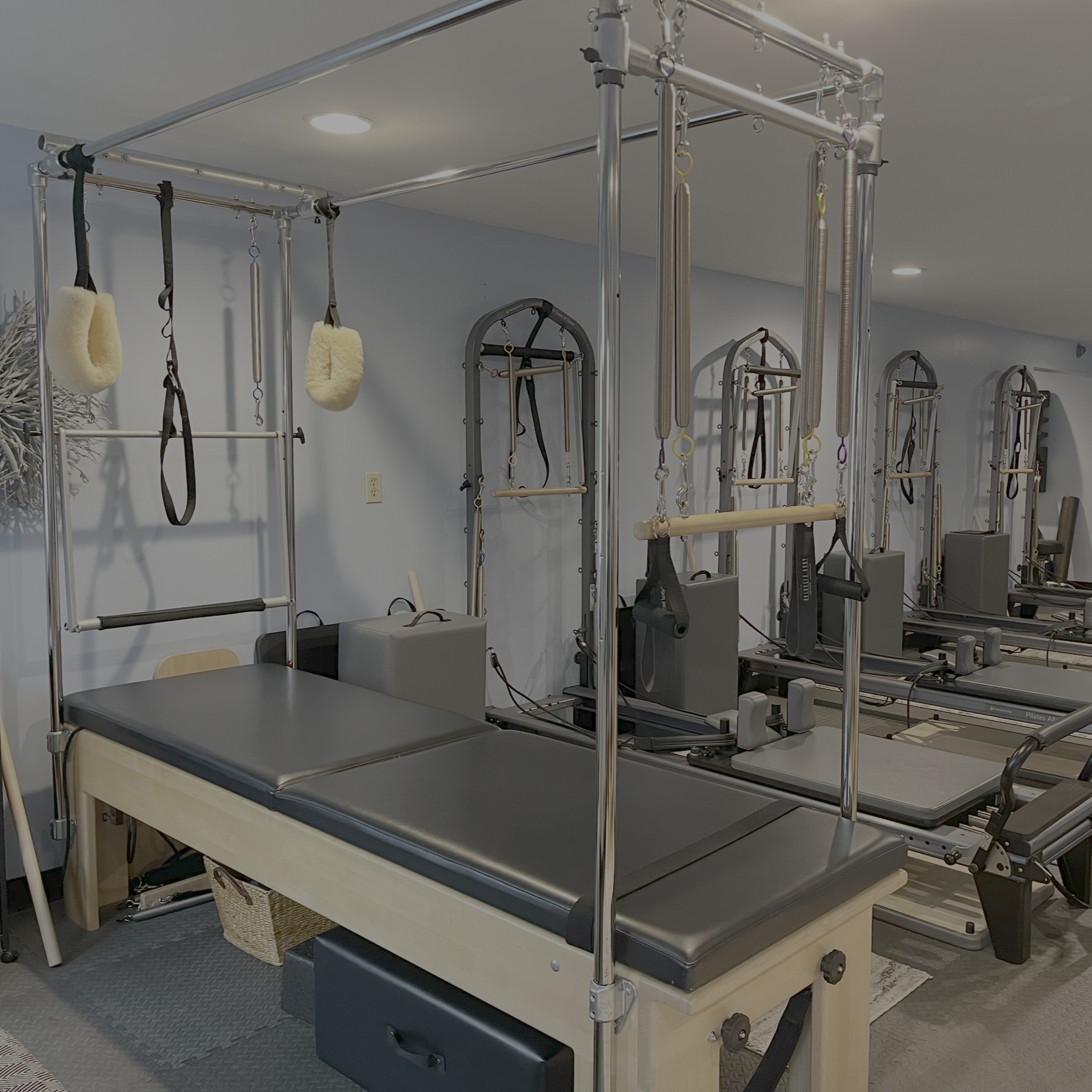 A Pilates reformer machine with various attachments and accessories in a Pilates studio.