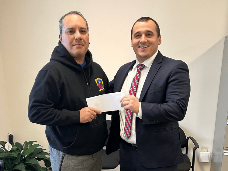 Attorney Jerry Kramer with a client holding a settlement check