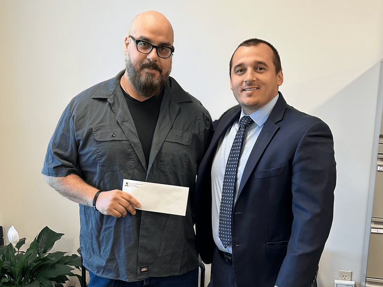 Attorney Jerry Kramer with a client holding a settlement check
