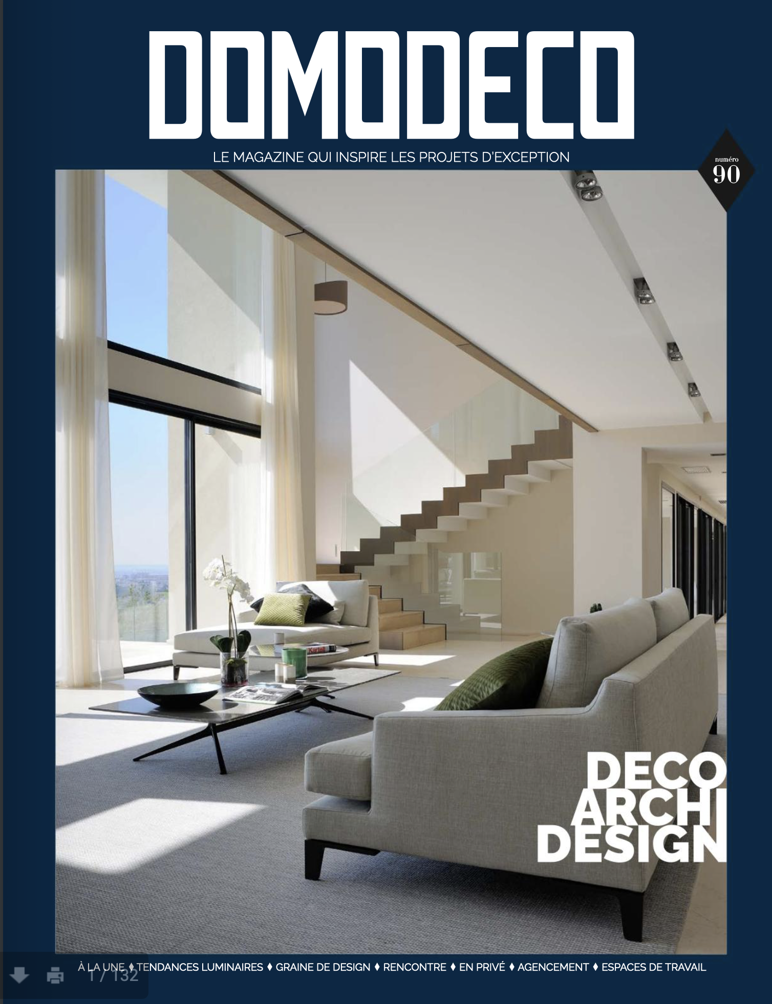 Couverture d'un magazine de design intérieur, intitulé 'DOMODECO', montrant un salon moderne lumineux avec canapé, table basse, grande fenêtre, escalier en bois et design épuré.