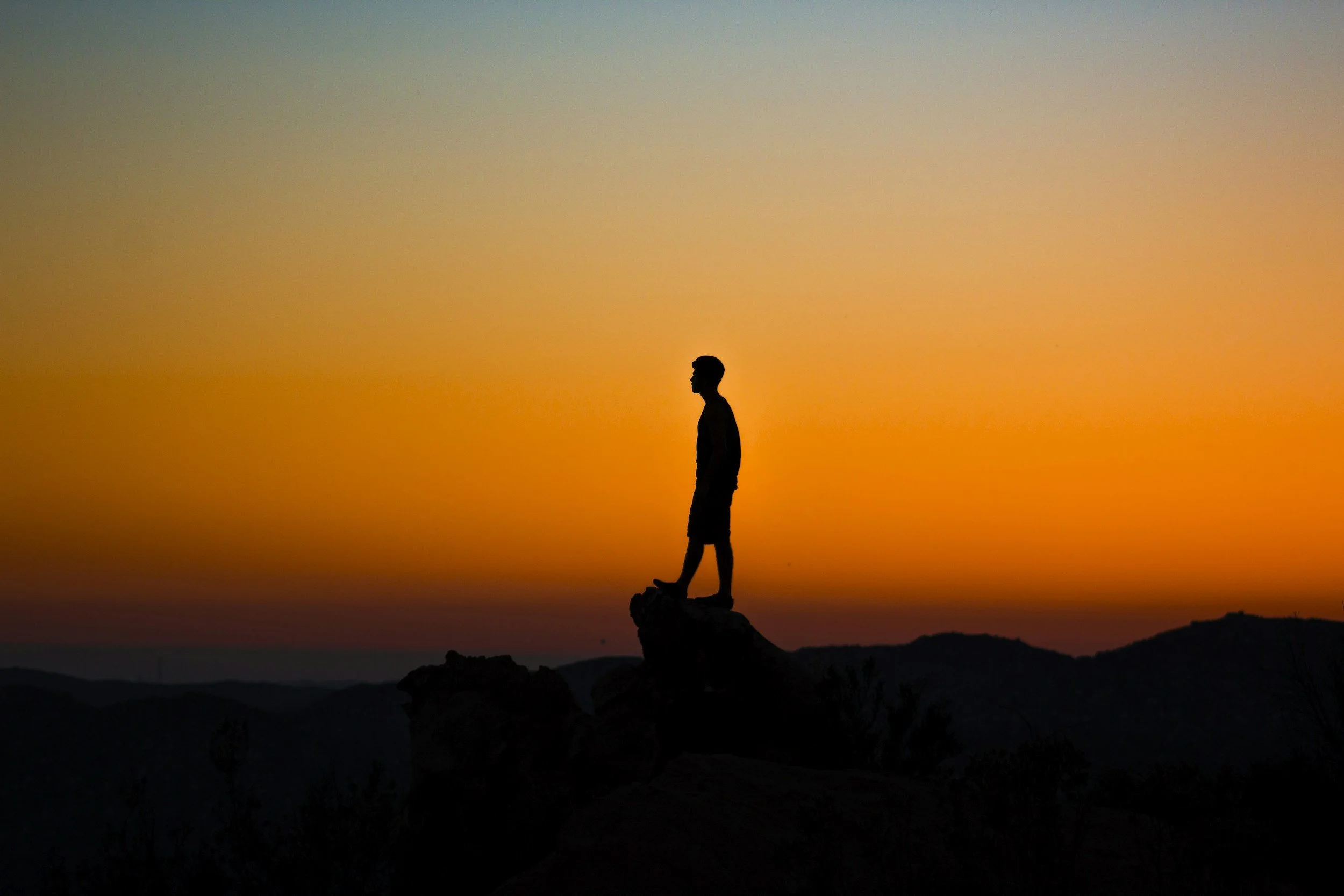 A man sitting on a rock, reflecting and building self-trust and emotional awareness