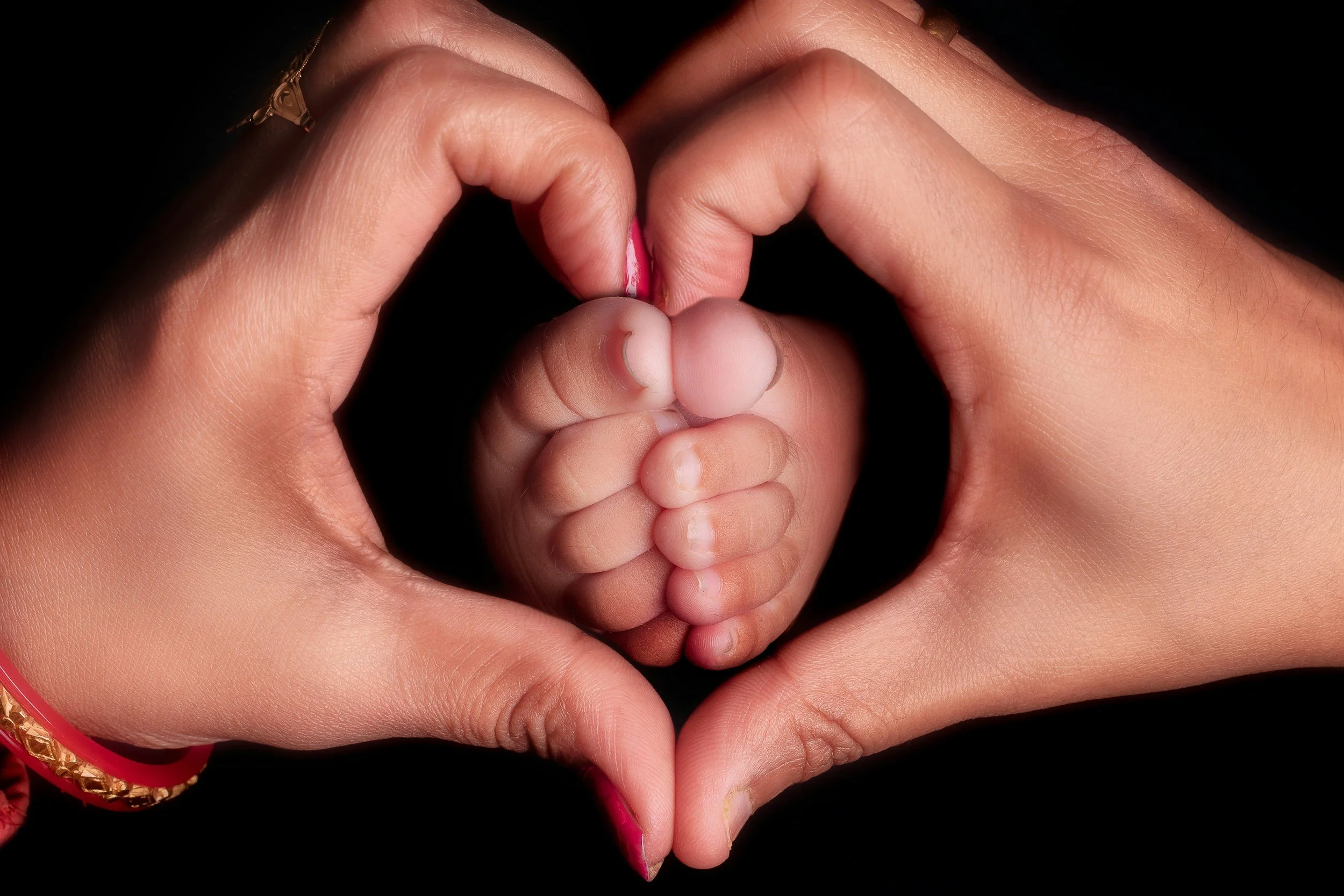Mother holding her infant’s hand, representing postpartum support and connection.