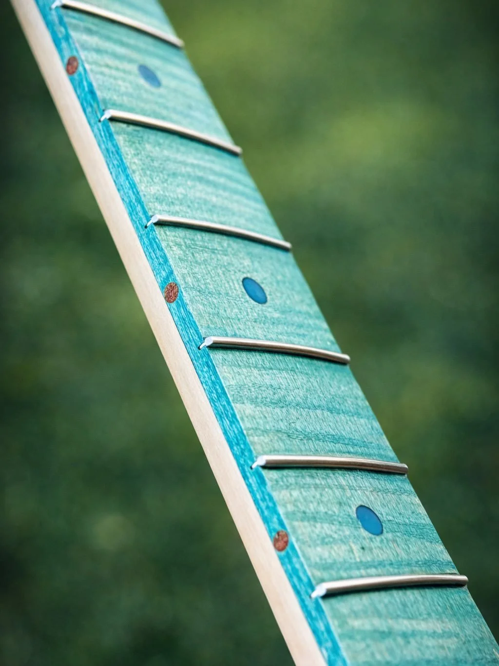A seaside-inspired commission in progress 🌊
Flame maple fretboard with ocean-toned stain, epoxy-coloured fret markers, and mahogany side dots. Frets are installed, with final finessing still to come.