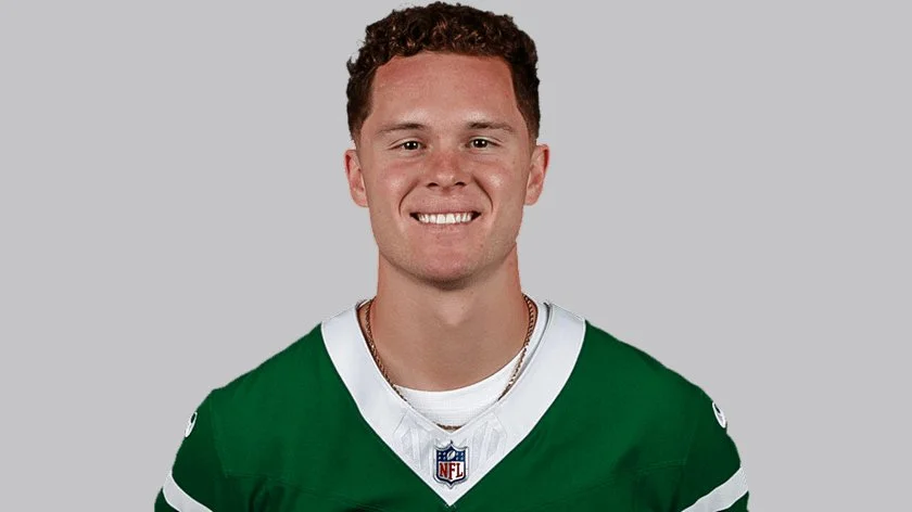 An NFL player adjusts his helmet on the field of a stadium.