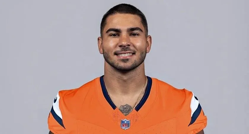American football player in orange jersey and white helmet running on field.