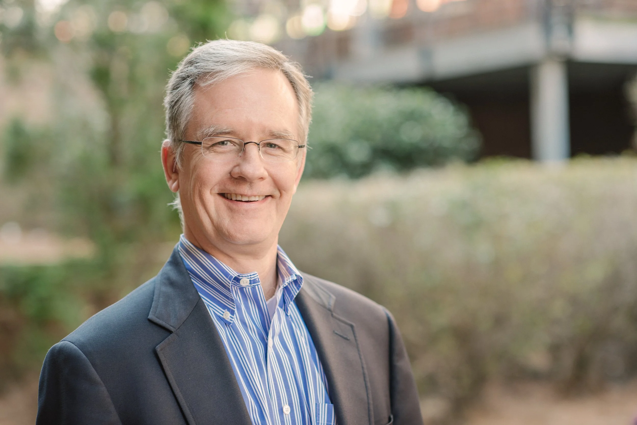 A middle-aged man with gray hair and glasses smiling