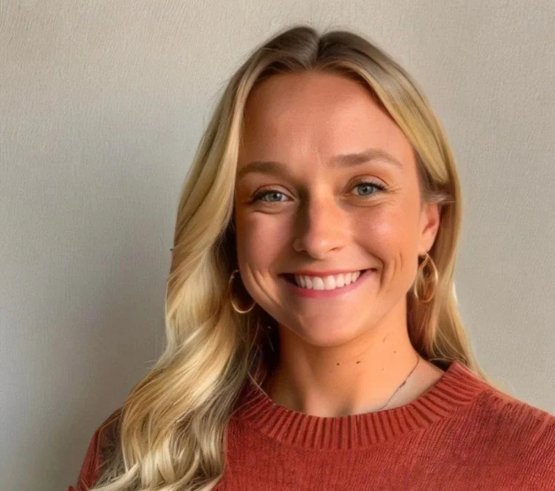 A smiling woman with long blonde hair, wearing a rust-colored sweater