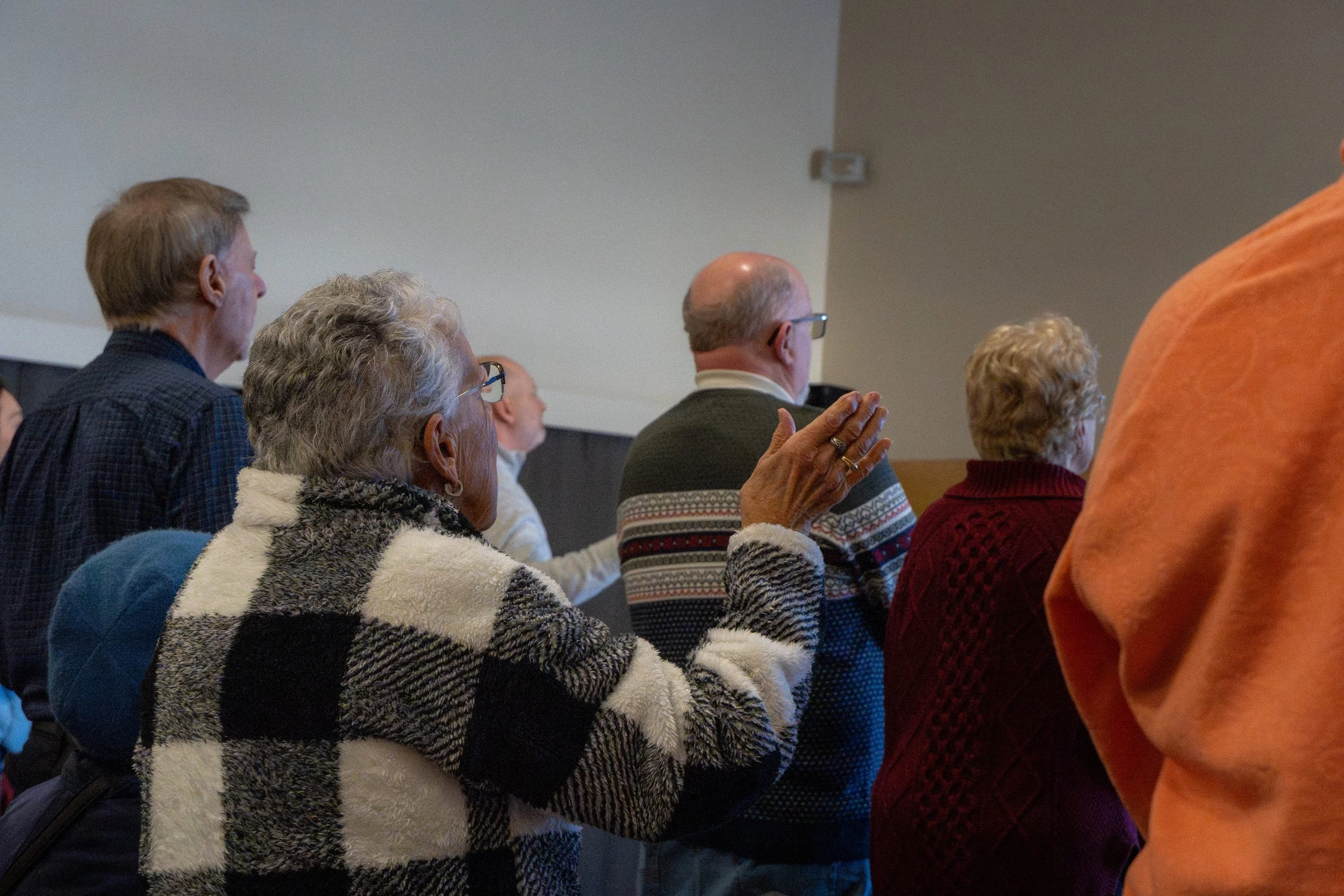 People attending a meeting or event, sitting and raising their hands.