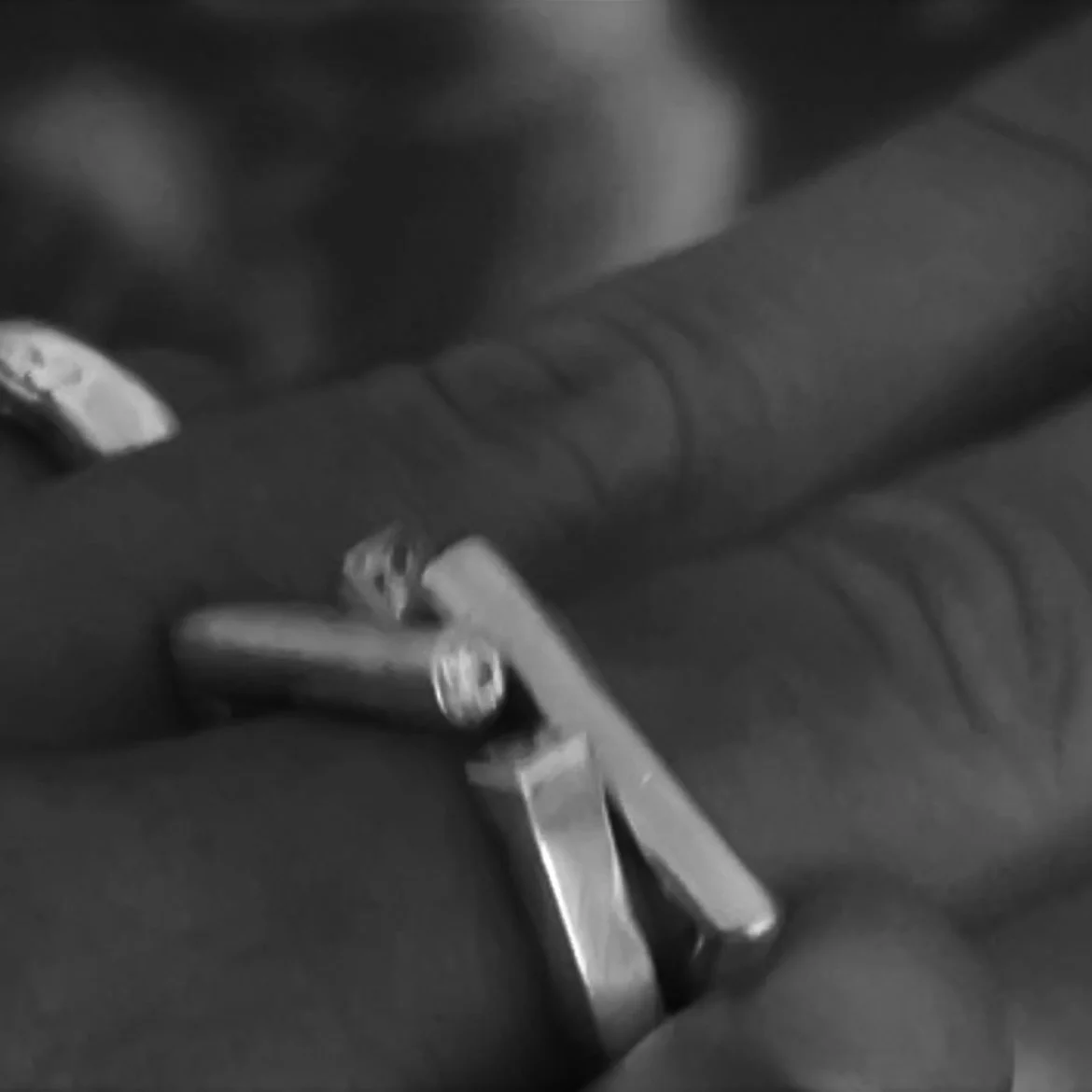 Close-up of a hand wearing a ring, resting on a leather surface with a textured pattern, in black and white.