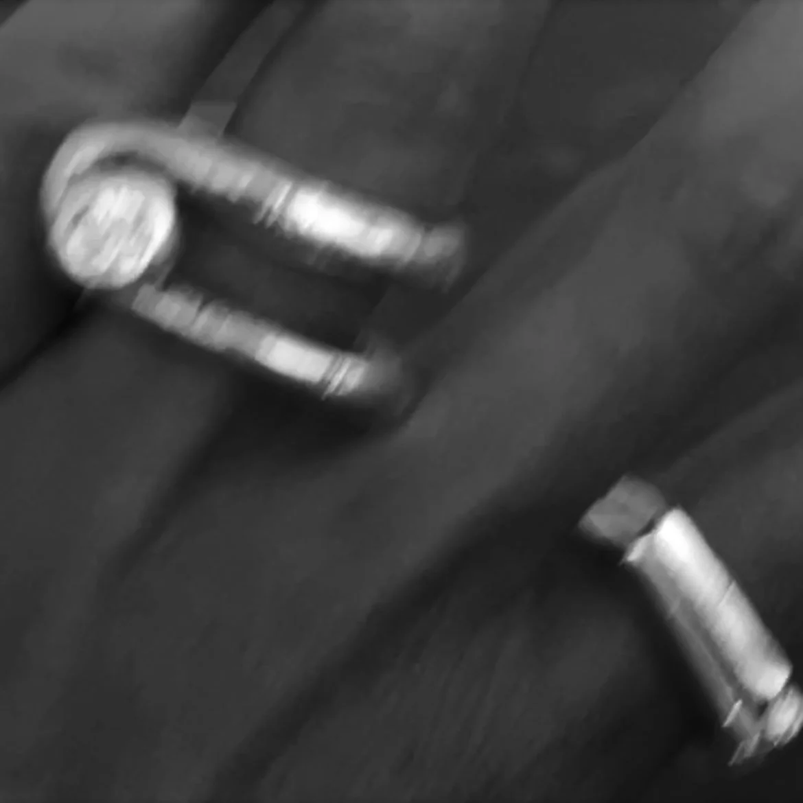 Black and white photo of a laptop keyboard with a partially visible wristwatch resting on it.