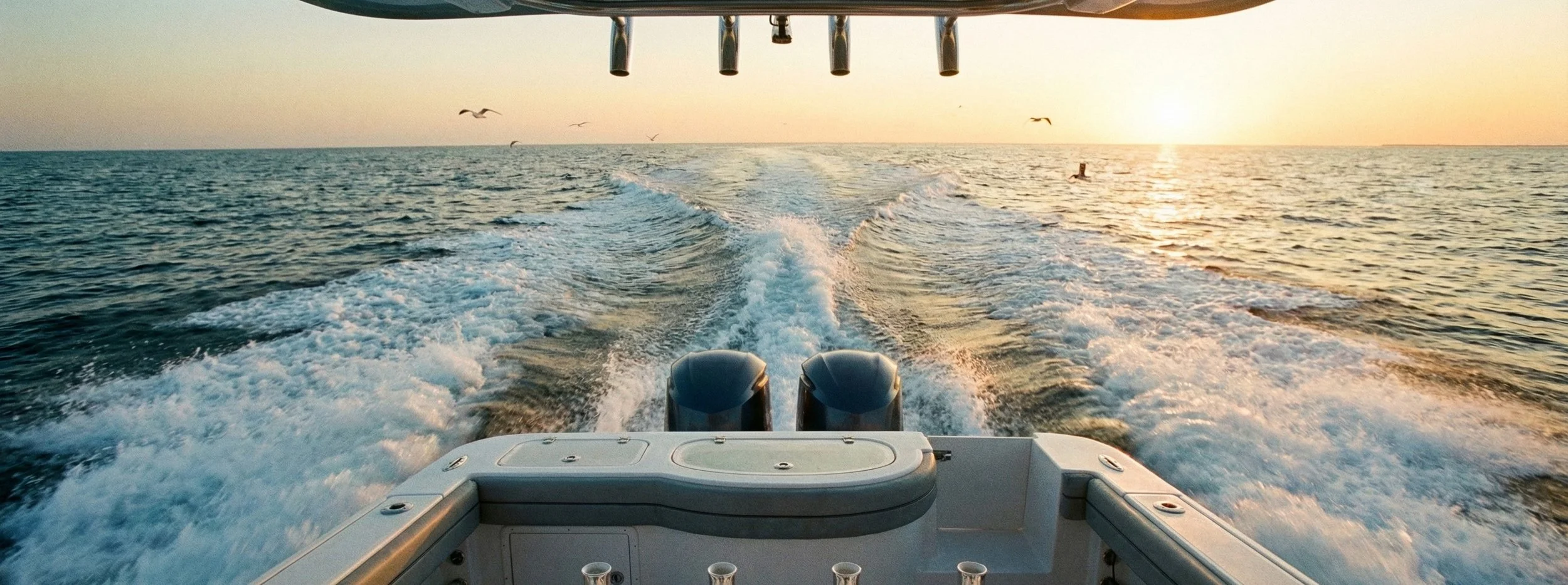 View over the twin engines and wake of a commercial charter boat at sunset, illustrating the Academy's philosophy of being 'built on the water, not in a classroom.