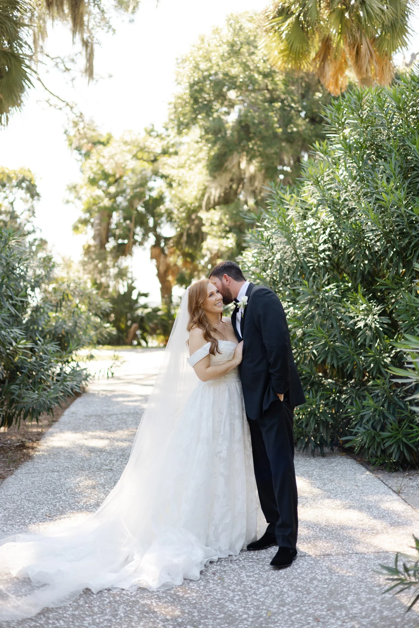 Romantic photo of a bride and groom beneath palm trees and greenery in the Jekyll Island Historic District.