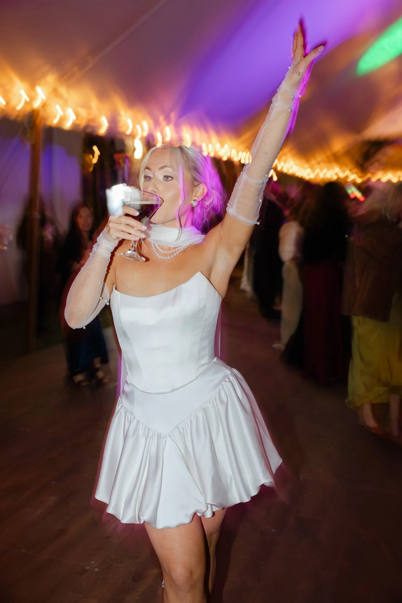Bride dancing with an espresso martini in a party dress