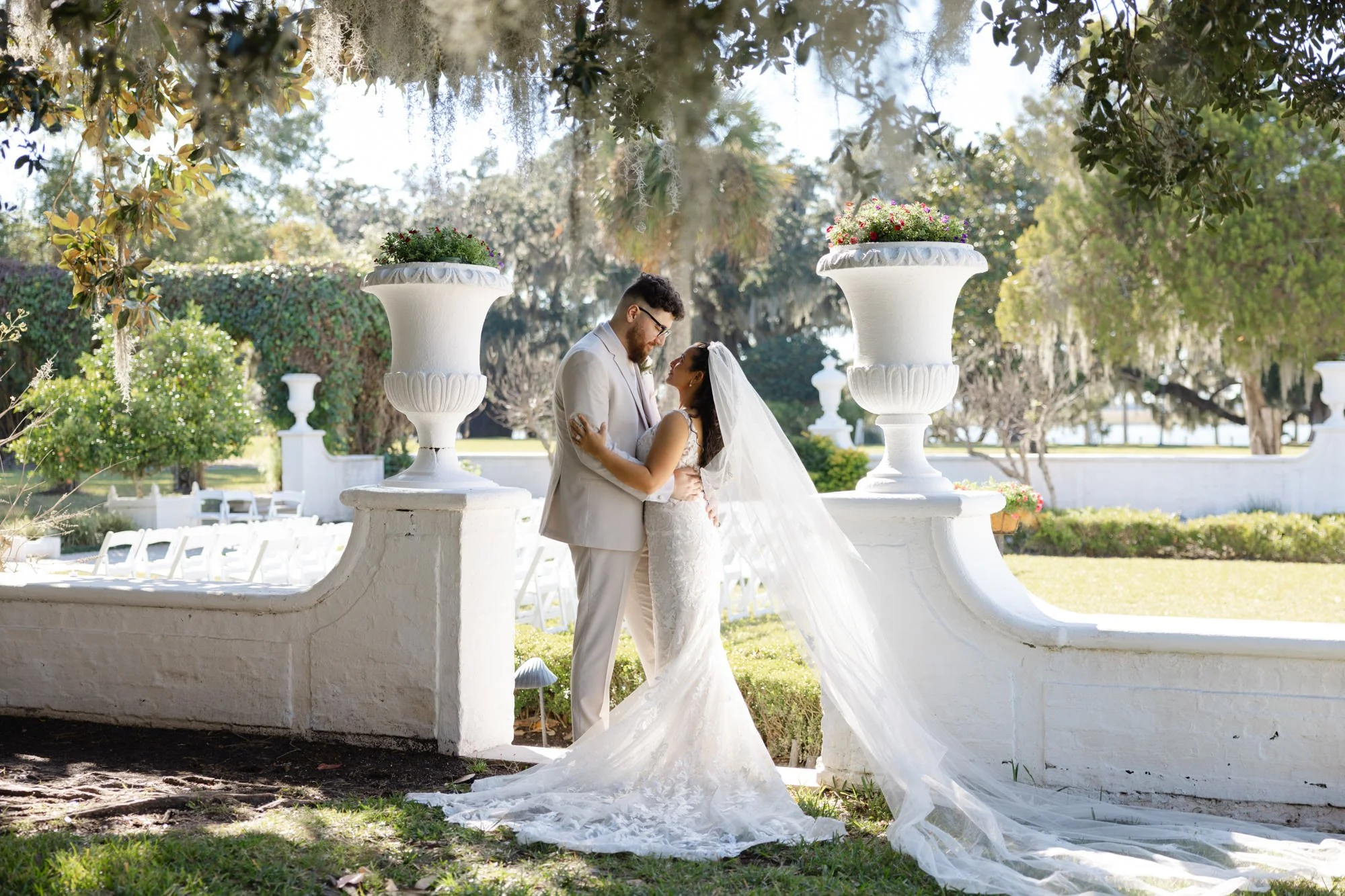 Bride and groom beneath moss covered oak trees beside the garden at Crane Cottage at Jekyll Island Club.