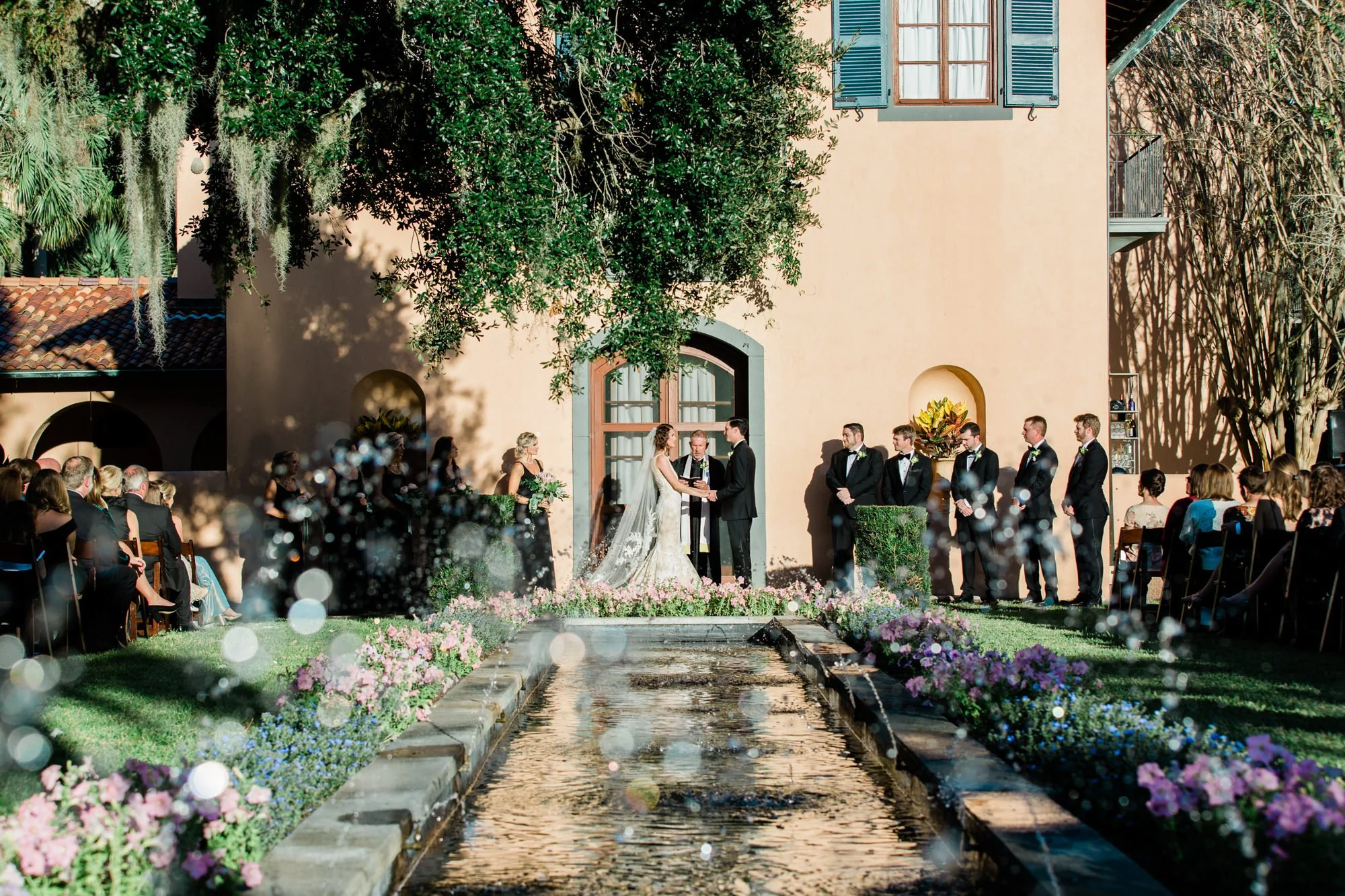 Wedding ceremony outside at Villa Mariana in the Jekyll Island Historic District with a fountain beneath a live oak tree.