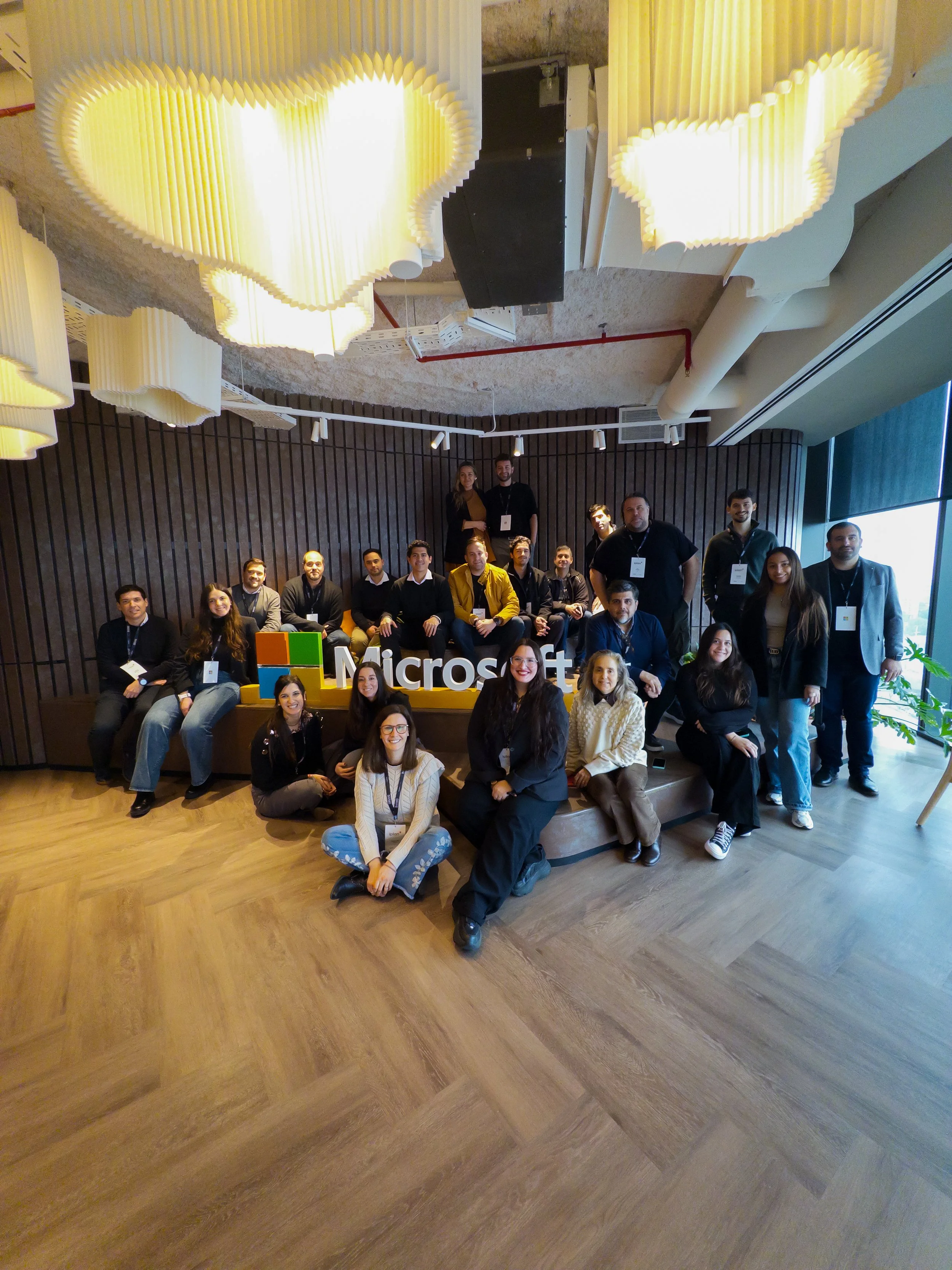 Un grupo de personas posando en un evento de Microsoft, con un cartel que dice 'Microsoft' y el logotipo de la compañía.