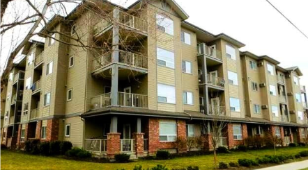 Multistory residential apartment building with balconies and exterior landscaping.