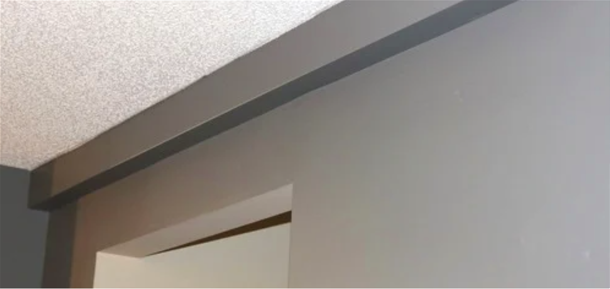 plumbing track installed and painted Close-up of a door frame with gray molding and a textured ceiling.