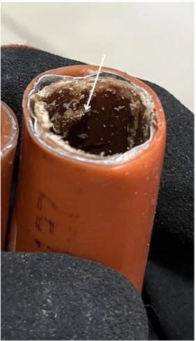 Close-up of a physical fuse with melted or burnt interior, showing damage from overheating.