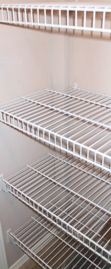 plumbing track installed and painted Empty white wire shelves inside a pantry or closet.