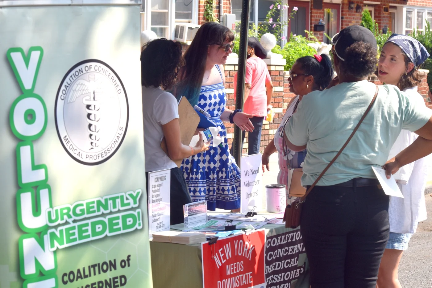 CCMP organizers on a lit table explain CCMP's program and sign up new volunteers.