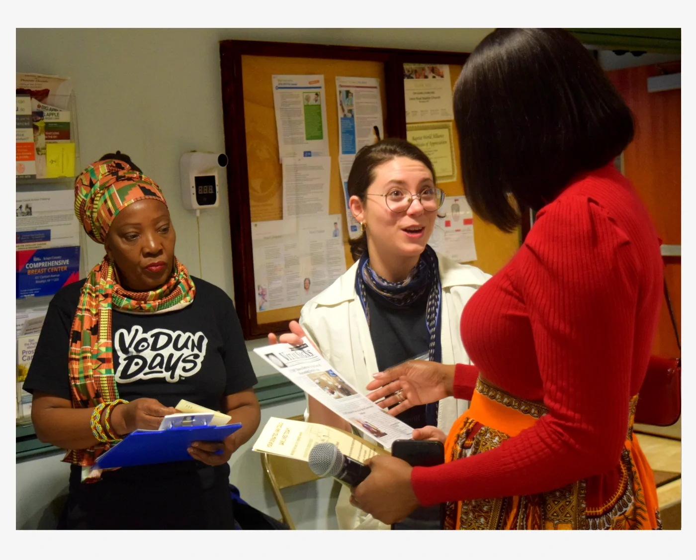 A volunteer showing off CCMP's newsletter to a new potential volunteer while another volunteer watches.
