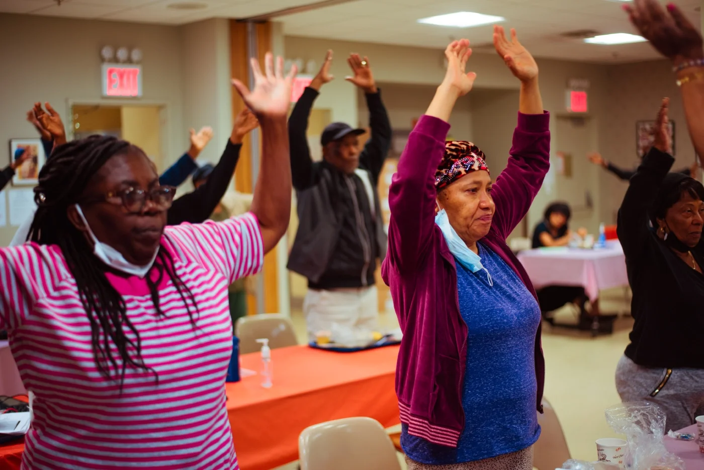 A large group of attendees to a CCMP medical and information session raise their hands, following the instructions of the presenting volunteer doctor.
