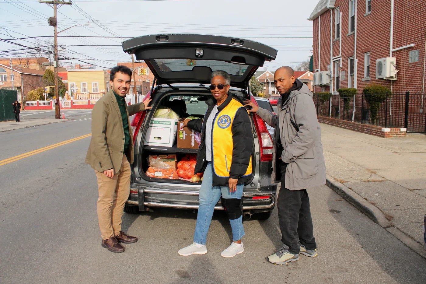 Three volunteer load food into a car.
