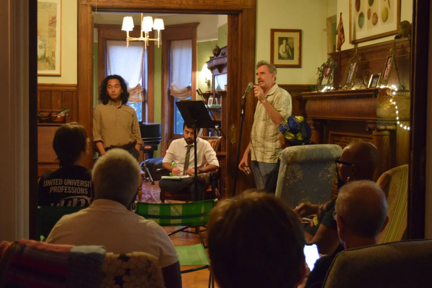A CCMP house meeting with a man at a microphone speaking to the crowd.
