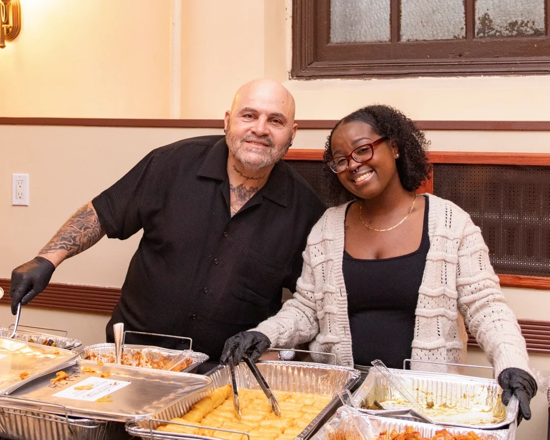 Two CCMP volunteer serving food at CCMP's event. 