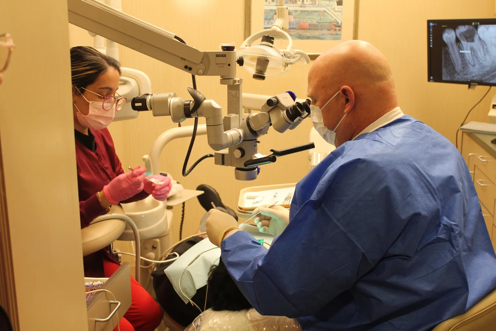 A volunteer endodontist performing a root canal with help from a dental assistant.