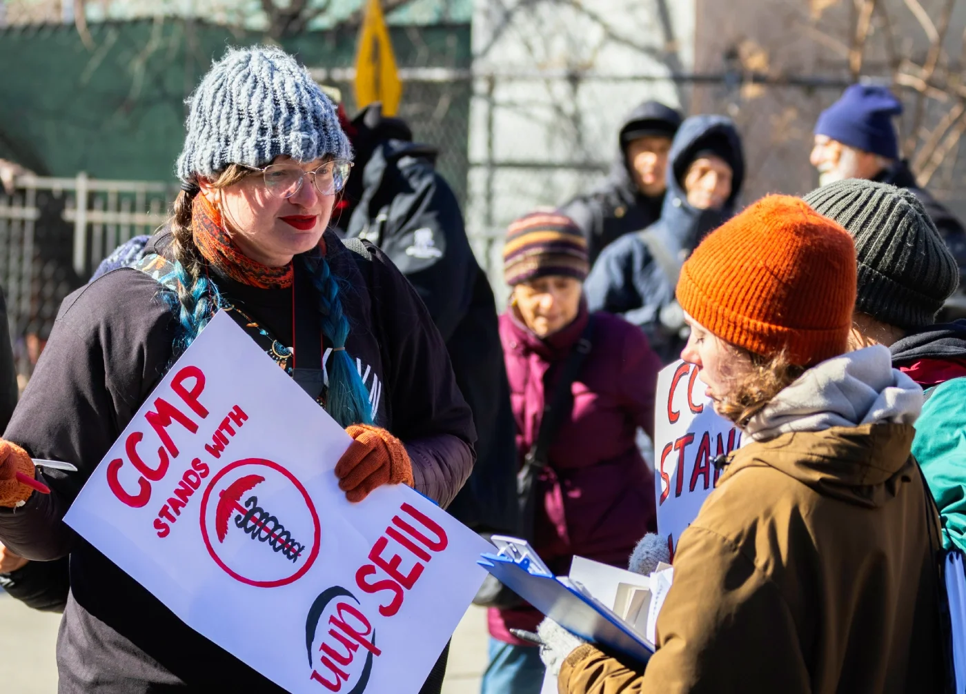 A CCMP organizer holding a picket sign that reads "CCMP stands with UUP SEIU" on a picket line.