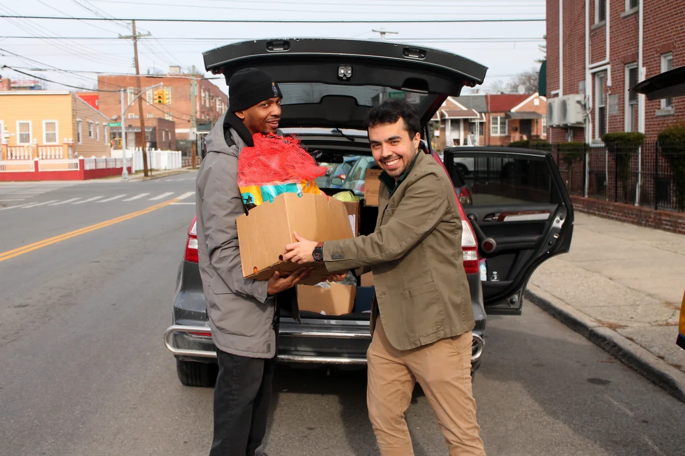 Two volunteer load food into a car.