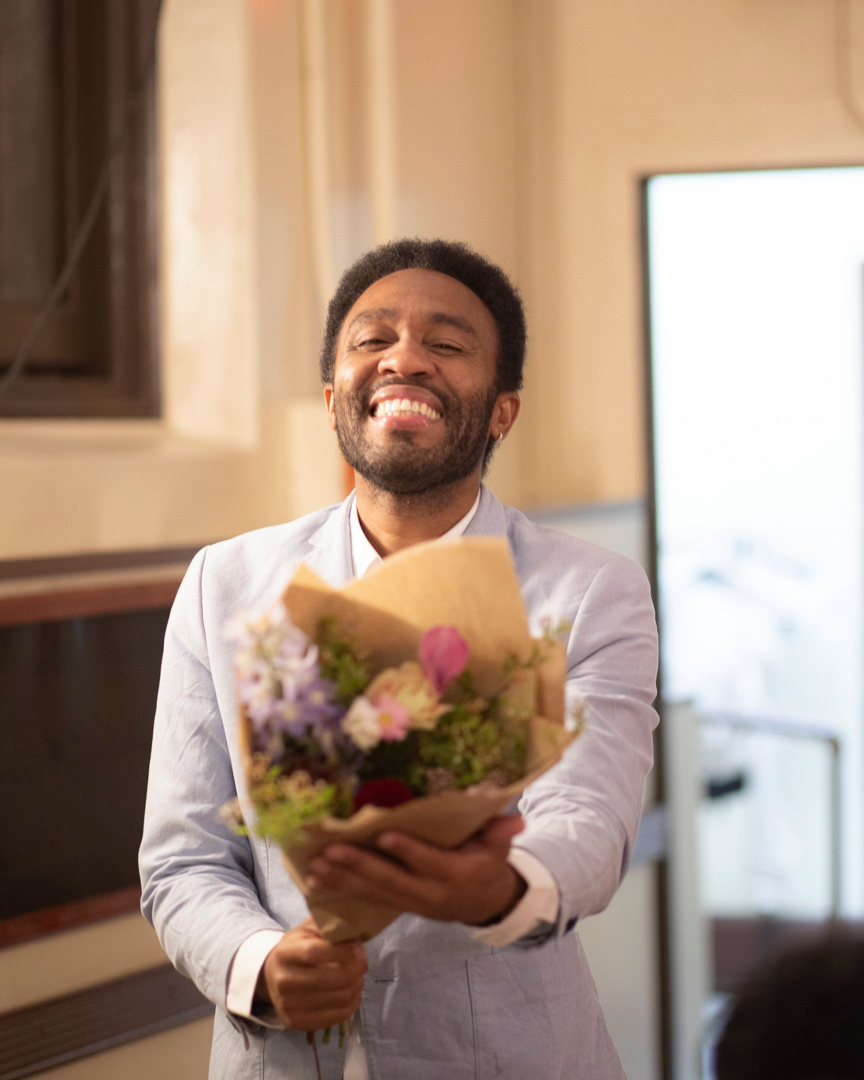 A CCMP volunteer holding a bouquet flowers and smiling from ear to ear.