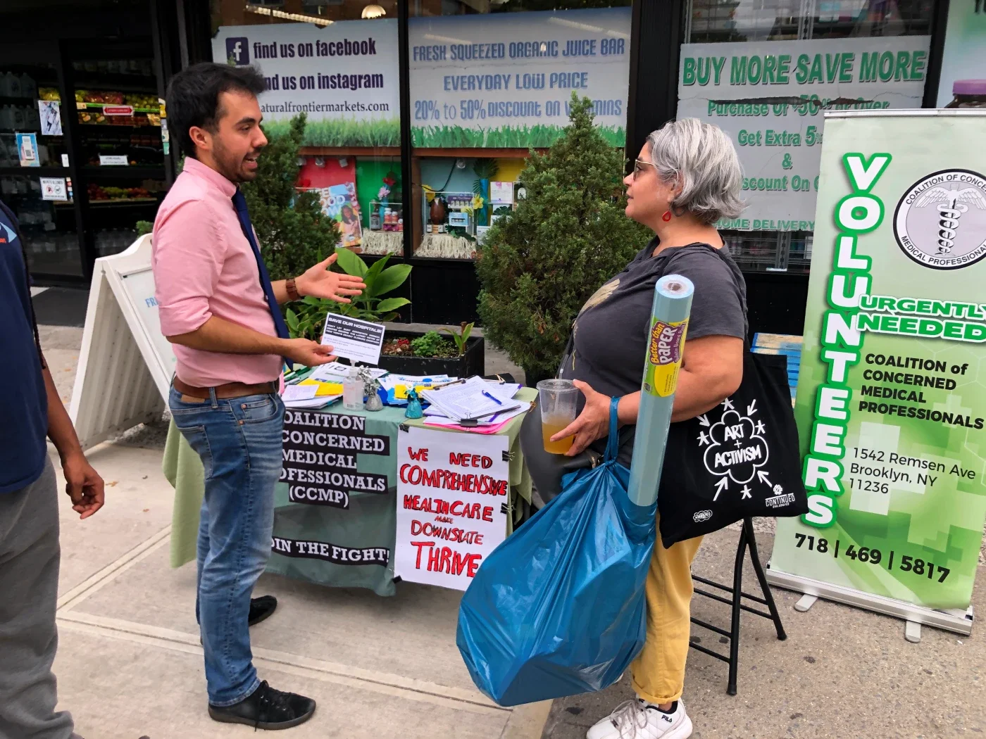 A CCMP organizer on a literature table in front of a local supermarket speaking to a resident about CCMP.