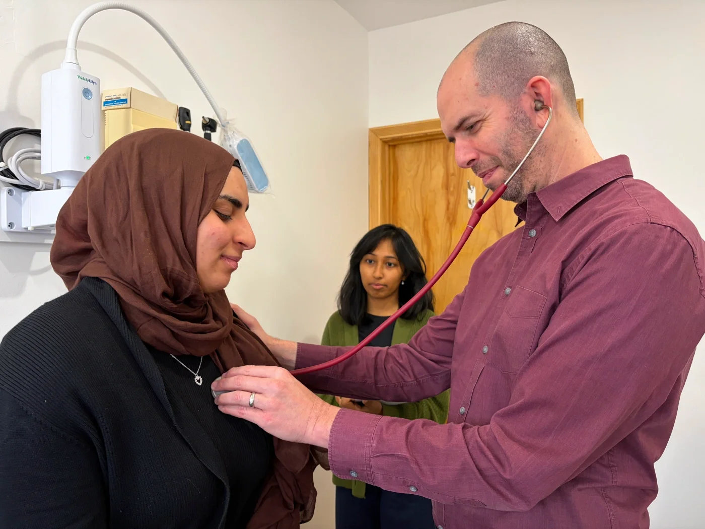 A doctor checks vitals with a stethoscope.