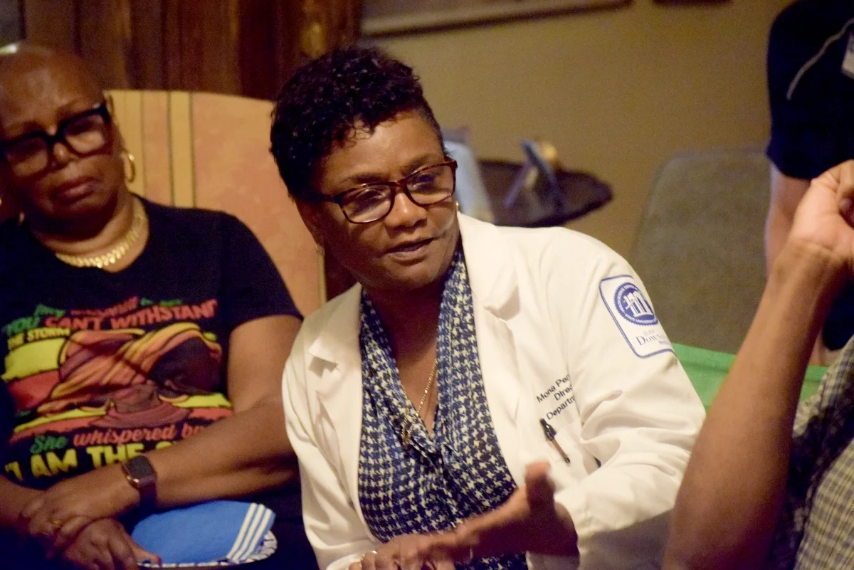 A volunteer doctor speaking at a house meeting while others listen.