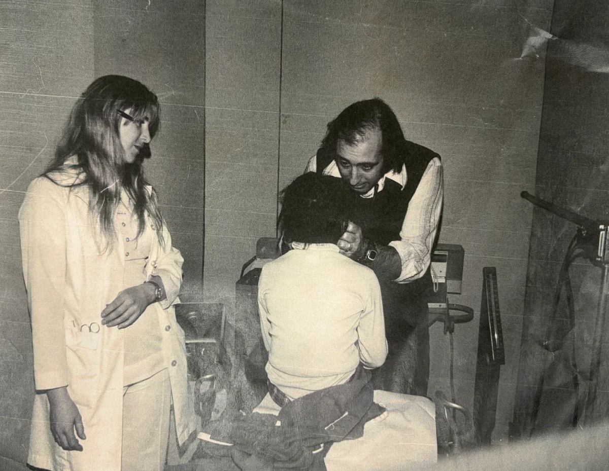 A volunteer doctor examining a child at donated medical appointment while a nurse accompanies him.