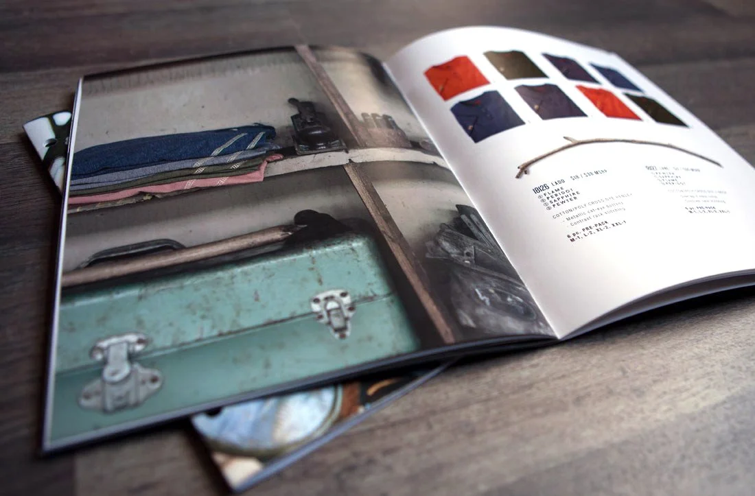 An open magazine displaying a vintage suitcase, clothing, and a camera on the left page, and fabric color swatches with product details on the right page.