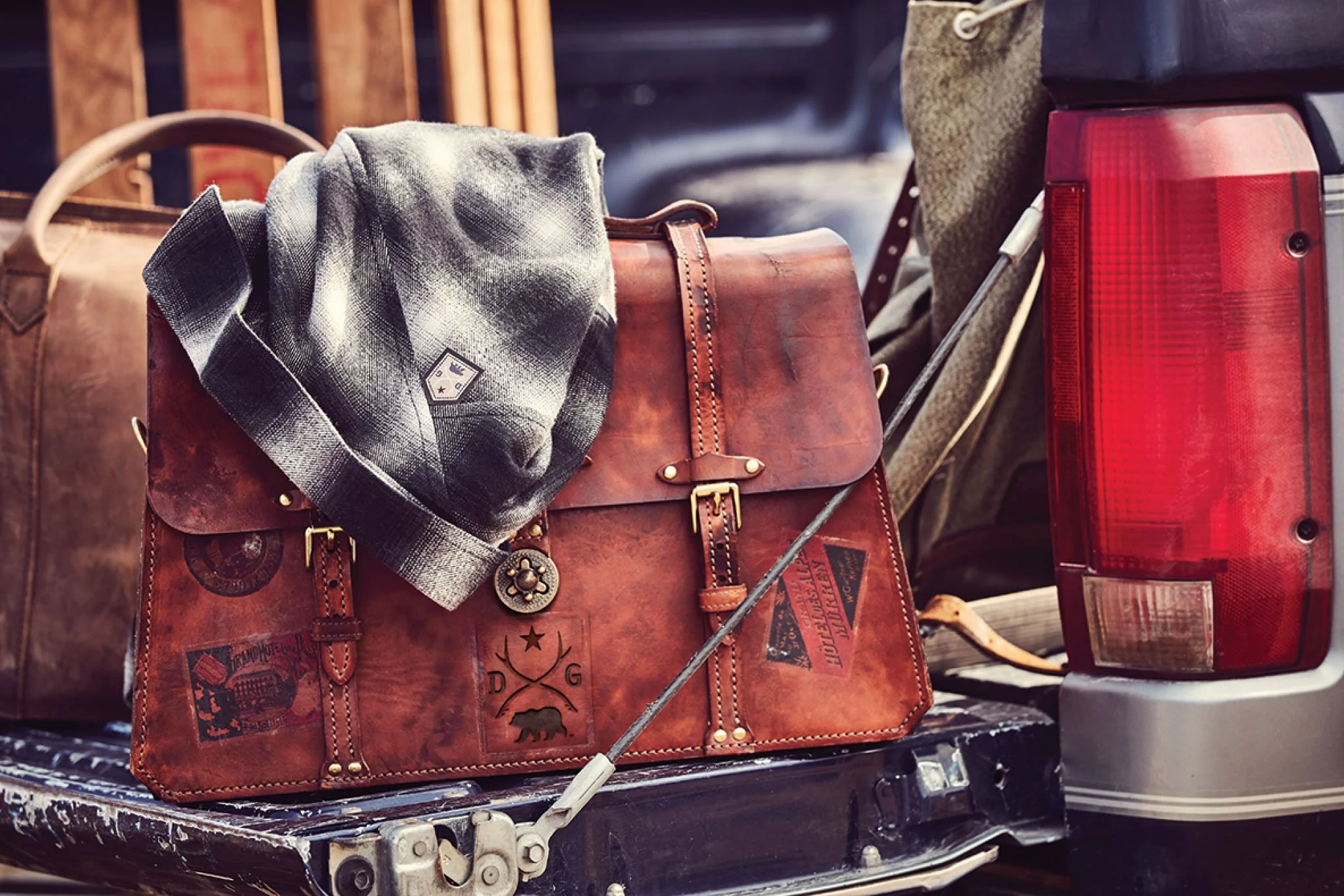 Travel bag and a hat on the tailgate of a vehicle, possibly during outdoor activity.