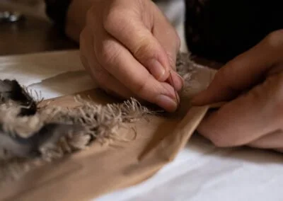 Person repairing or restoring a fabric or textile item on a wooden surface.