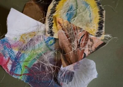 Crumbled pieces of torn and colorful drawings or artwork on paper with frayed edges.