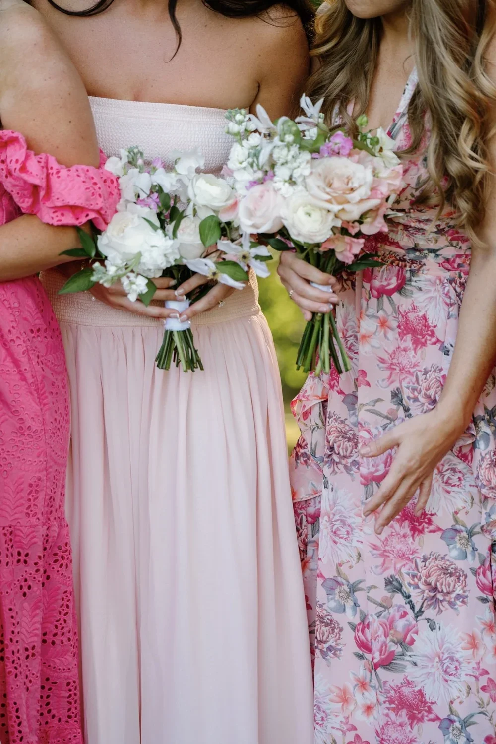Two women dressed in pink dresses holding bouquets of flowers.