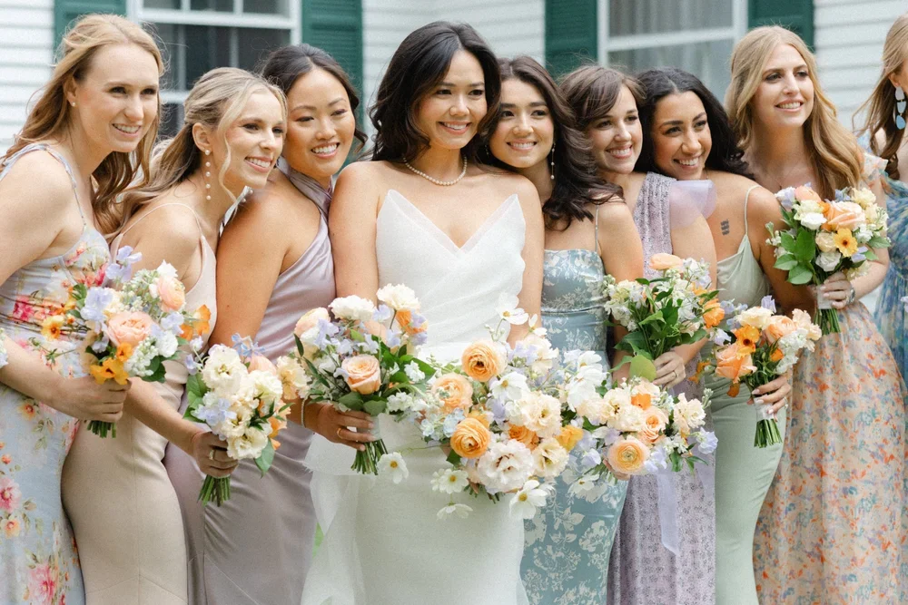 A group of women, including a bride in a white wedding dress, holding bouquets of flowers at a wedding celebration.