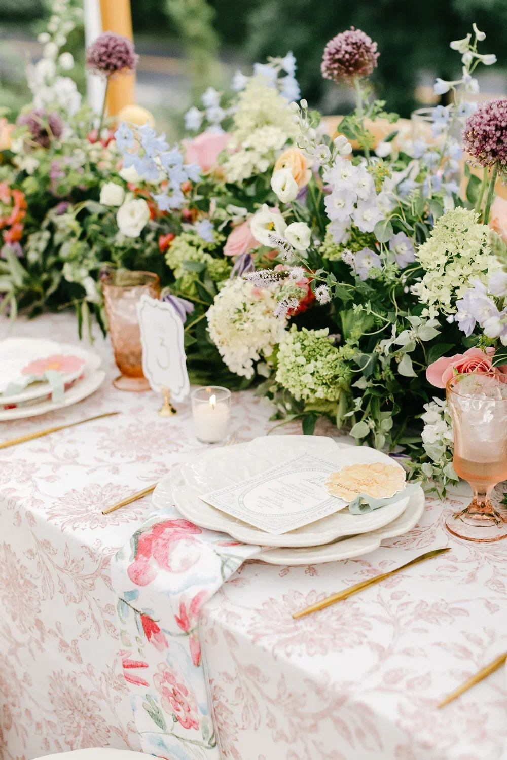A table setting with floral arrangements, candles, and elegant dinnerware for a celebration or wedding reception.