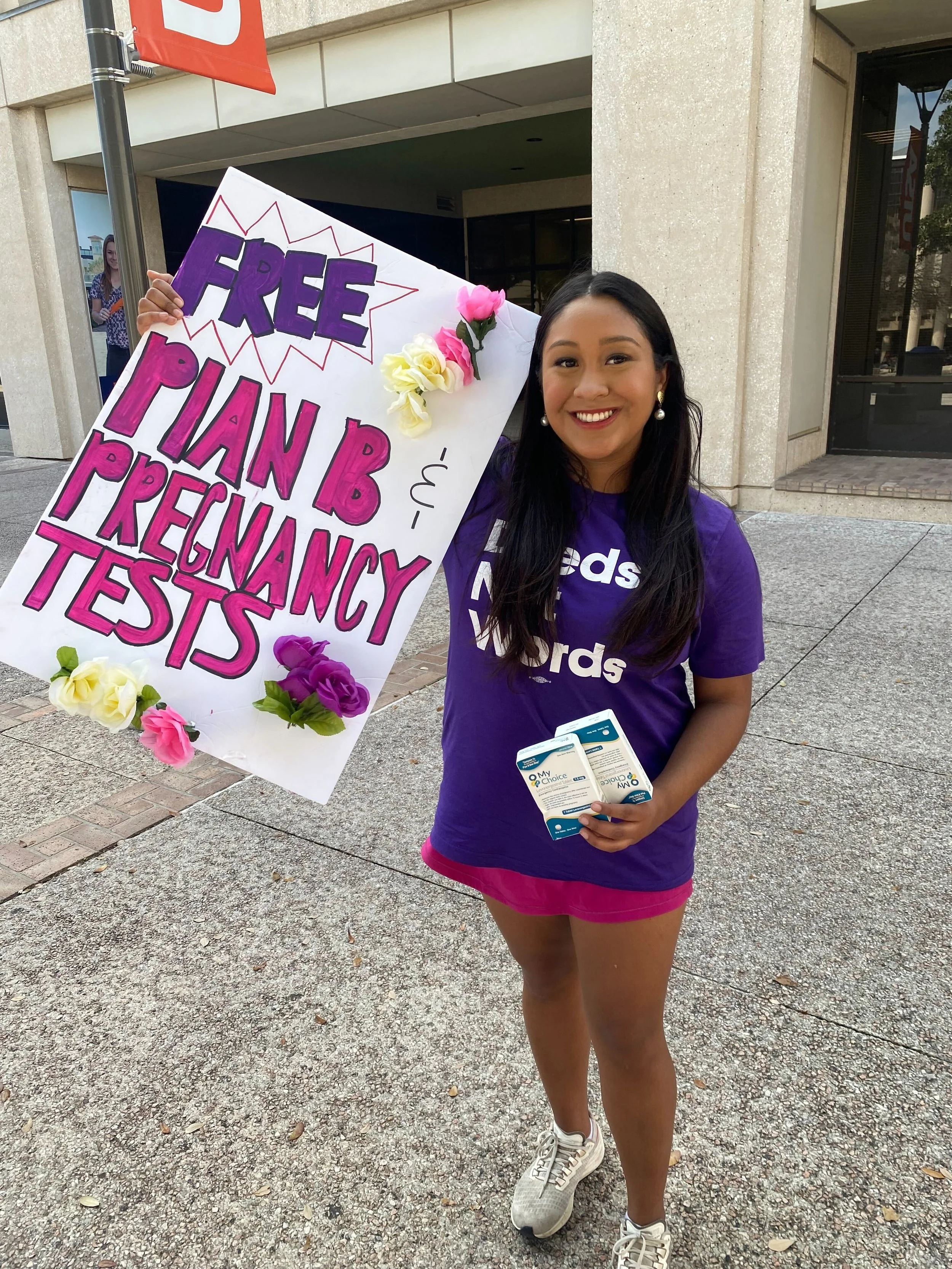 Deeds Not Words student holds up a sign that reads "FREE Plan B and Pregnancy tests"