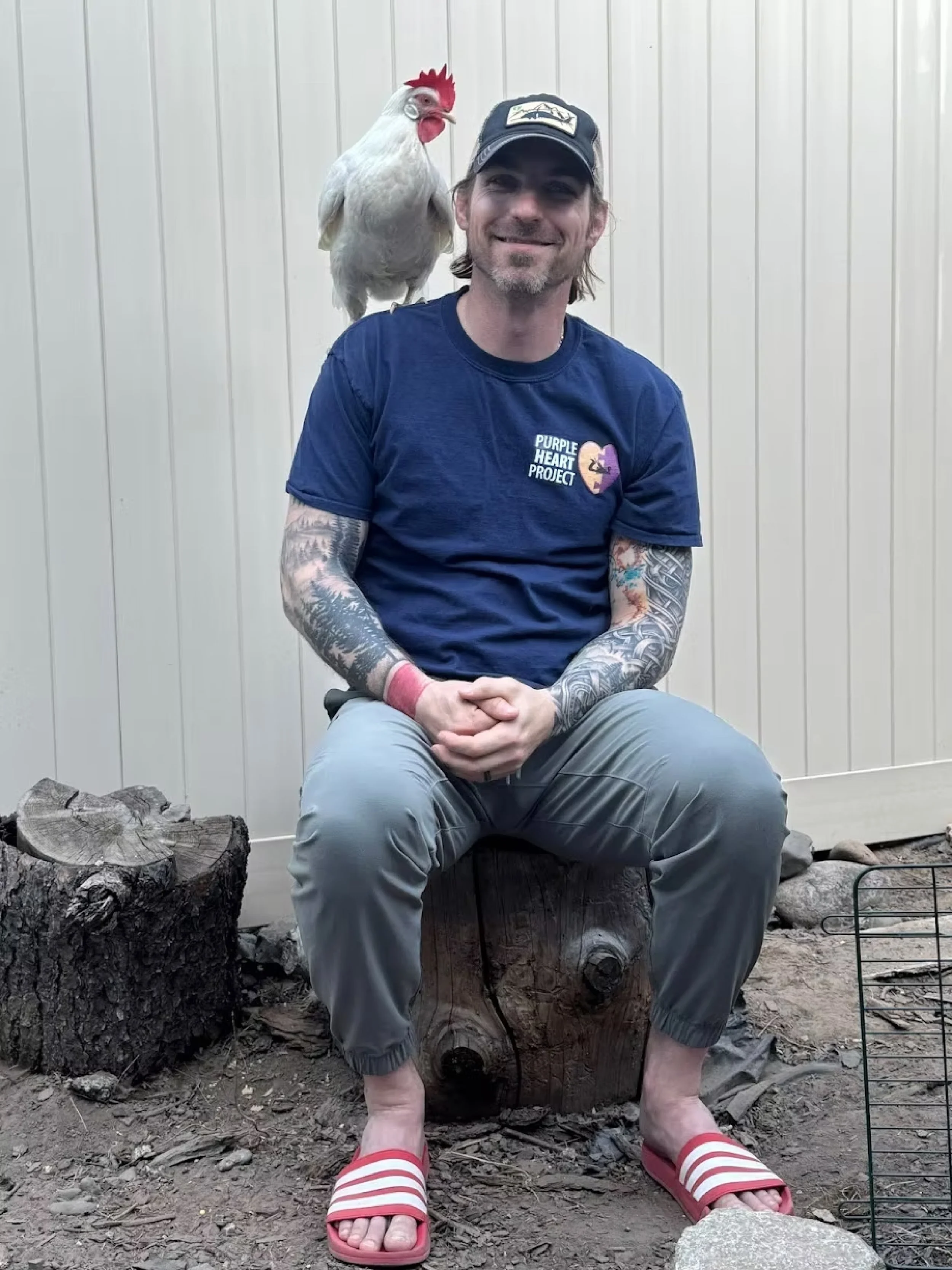 Aaron Croft with a chicken perched on his shoulder, smiling at the camera.