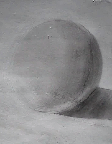A large, smooth sphere resting on a flat surface with a shadow cast to the right.