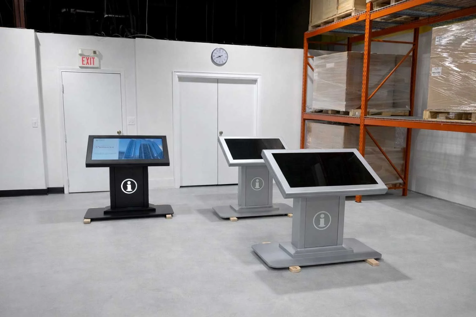 Indoor digital signage kiosks staged in a manufacturing facility, showcasing custom metal fabrication and touchscreen integration by B&F Solutions Inc.