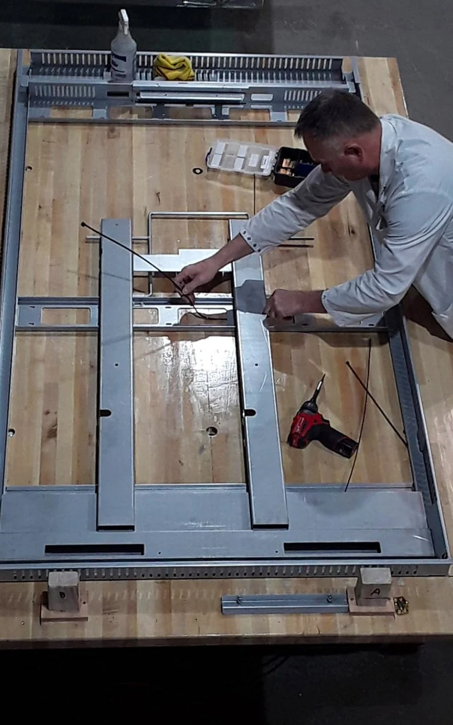 Technician assembling a custom metal frame for an indoor digital signage display during fabrication at B&F Solutions Inc.